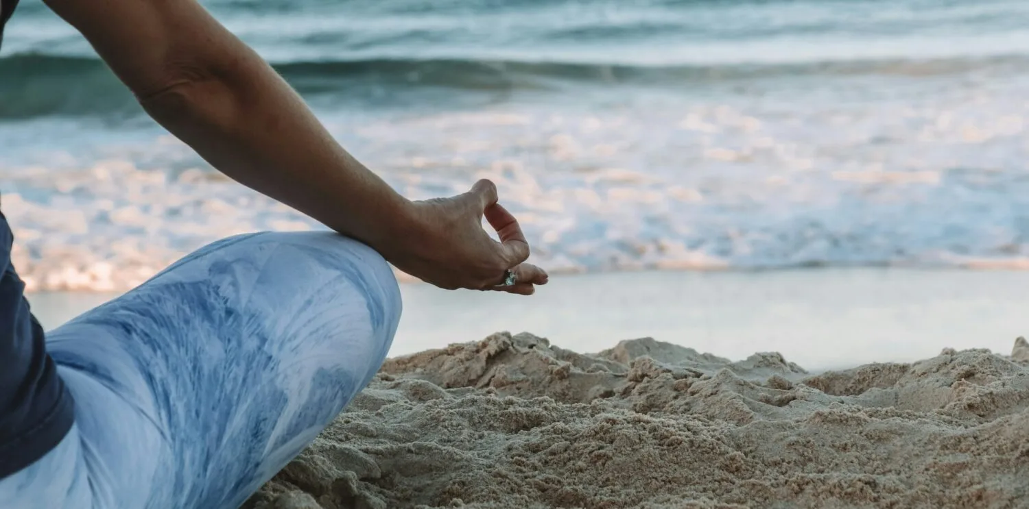 person in blue shorts sitting on beach shore during daytime